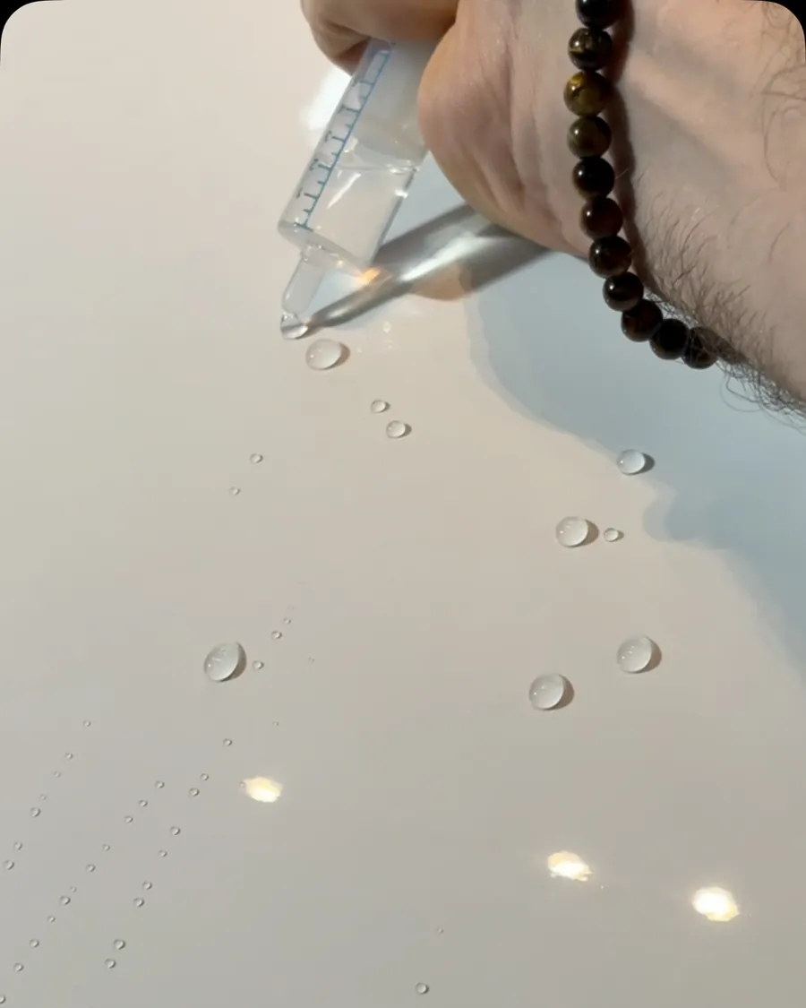 Gotas de água escorrendo e formando bolinhas sobre pintura branca vitrificada